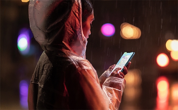 Femme tenant l'iPhone XR sous la pluie.